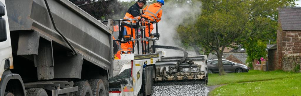 A highways crew undertaking surface dressing on a road.